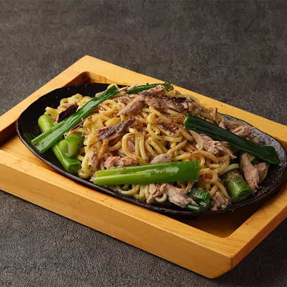 Fried noodles with dried bonito flakes and grilled green onions in soy sauce
