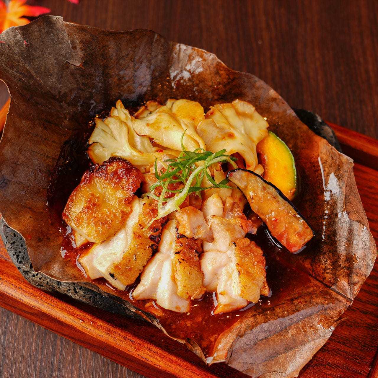 Chicken and white maitake mushrooms grilled on a magnolia leaf