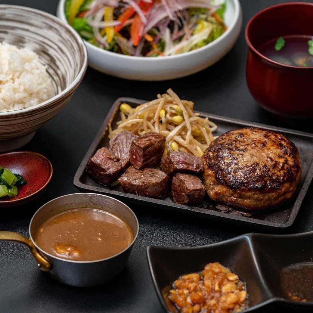 一份包含满铁牌鲜嫩多汁的汉堡牛排和切片日本黑毛牛肉牛排的组合拼盘。