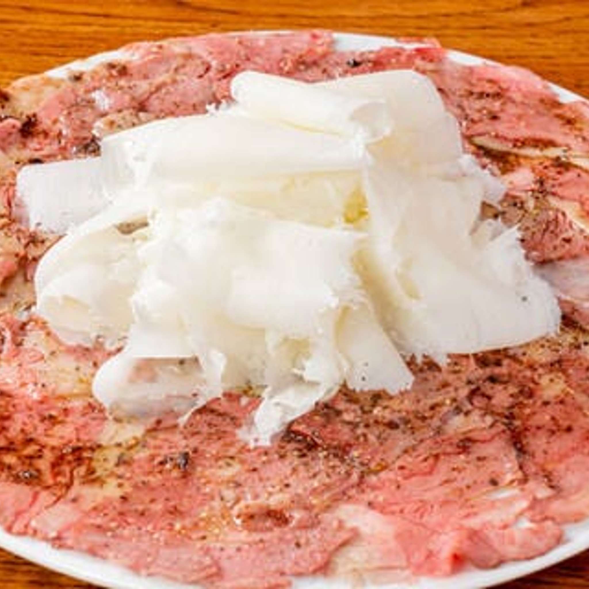 皿一面に広がる牛肉のカルパッチョ　ふわふわチーズがけ
